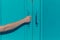 Young female hand grabbing blue door