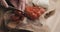 Young female hands slicing cherry tomato on wooden board