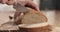 Young female hands slicing rye wheat rustic bread on cutting board