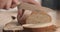 Young female hands slicing rye wheat rustic bread on cutting board