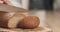 Young female hands slicing rye wheat rustic bread on cutting board