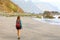 Young female hiker discovering wild paradisiac beach in Tenerife Island. Back view traveler girl arrives on hidden amazing beach