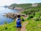 A young female hiker standing above the atlantic ocean overlooking the rugged coast of Newfoundland and Labrador, Canada