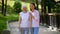 Young female hugging elderly woman with walking frame outdoors, rehabilitation