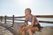 Young female jogger resting on the coastline