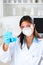 Young female Lab Tech holding up a flask of blue chemicals in laboratory setting. Vertical format