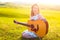 Young female left-handed musician playing guitar instrument at nature