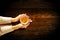 Young female manicured hands holding cup of coffee with fresh foam on dark rustic wooden table background.