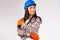 Young female mechanic in hard hat and protective builder gloves posing on a gray background. Gender equality, fearless