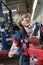 Young female mechanic in protective workwear working on machinery part in automobile repair shop