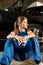 Young female mechanic sitting near the black car