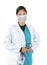 Young female medical professional wearing surgical mask, green scrubs and a lab coat holding a stethoscope in one hand and the