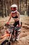 Young female motocross racer in safety helmet riding on her motorcycle in off road adventure