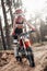 Young female motocross racer in safety helmet riding on her motorcycle in off road adventure