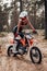 Young female motocross racer in safety helmet riding on her motorcycle in off road adventure