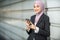 Young Female Muslim Entrepreneur smiling, holding her smartphone.