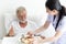 Young female nurse take care a senior retirement male serving breakfast on bed