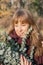 Young female in outerwear holding and looking at eucalyptus in park