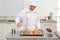 Young female pastry chef pouring chocolate sauce onto croissants at table