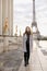 Young female person standing on Trocadero square near gilded statues and Eiffel Tower.