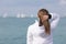 Young female person stands on seashore and looks away, rear view