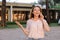 Young female person talking by sartphone outside, wearing blouse.