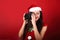Young female photograph making the photo on red background holding the camera in santa clause clothing