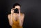 Young female photograph in yellow top holding camera and makeing the photo on dark background with empty copy space. Closeup port