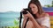 Young female photographer relaxing near ocean taking picture of something