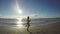 Young female putting on headphones and going for long a run on the beach