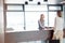 Young female receptionist looking at businesswoman signing document in office