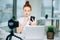 Young female redhead blogger with laptop recording video at home and take selfie