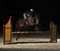 Young female rider on bay horse jumping over hurdle on equestria