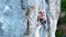 Young female rock climber trying to climb on a cliff, searching, reaching and gripping hold.