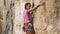 Young female rock climber trying to climb on a cliff, searching, reaching and gripping hold.