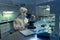 Young female scientist in coveralls looking in microscope