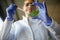 A young female scientist holds a green leaf sample ready for analysis at the university laboratory. Science, chemistry, lab,