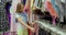 Young female shopper examines clothes from a rack in a mall store. Portrait of a shopaholic woman shopping in a fashion