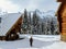 A young female snowshoer walking in between two wood cabins during the winter in the remote snow covered forests of Fernie