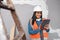 A young female South Asian construction worker uses tablet to log project