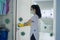 Young female spraying door with disinfectant liquid