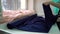 Young female spreading roll of blue satin fabric on table in fashion atelier