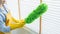 Young female spring cleaning house interior holding a duster for wiping dust dusting furniture at home