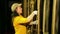 A young female stage worker in gloves removes the mount from a cable lifting mechanism of a theater curtain