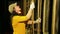 A young female stage worker in gloves removes the mount from a cable lifting mechanism of a theater curtain and lifts it