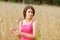 Young female stands in crop field holding flower