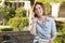 Young Female Student Outside Using Cell Phone Sitting on Bench