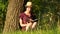 Young female student reading a book in the Park. Culture, reading, education. Girl sitting by the tree. Camera movement.