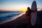 Young female surfer on beach in sunset