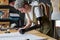 Young female tailor bending over table with piece of fabric while working